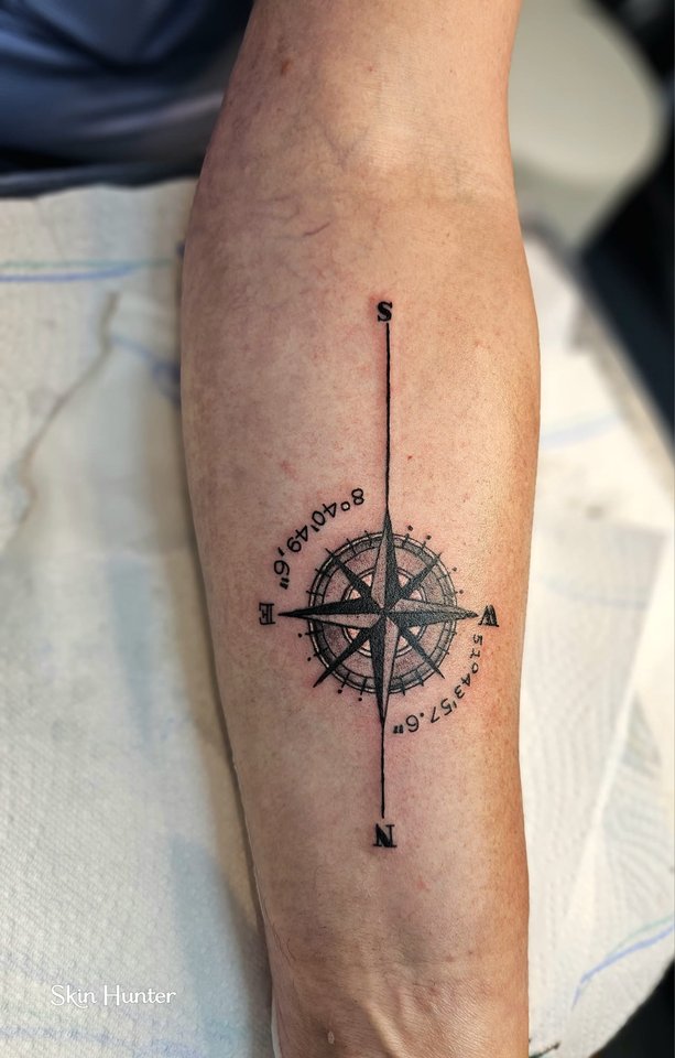 Kompassrose mit feinen Linien und Schrift am Unterarm