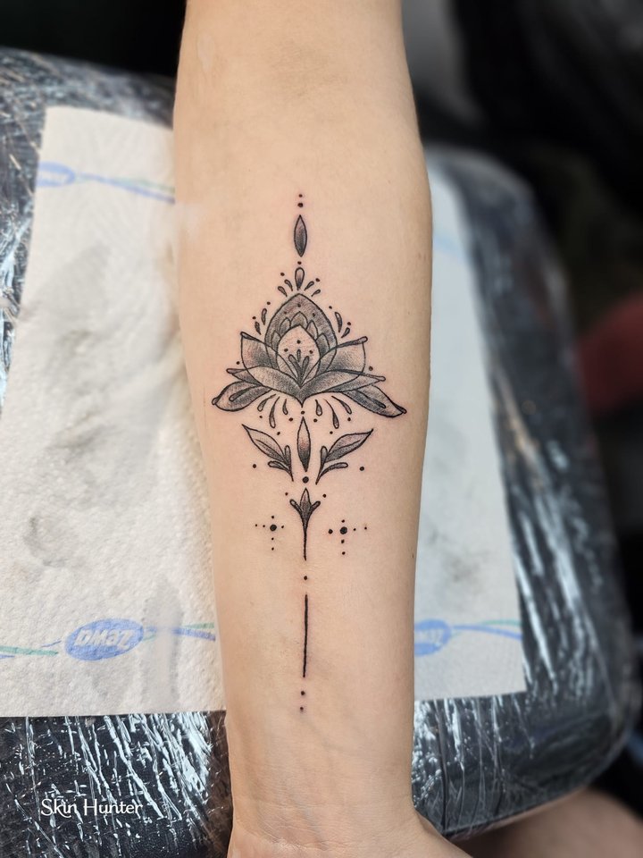 Ornamentales Fineline-Tattoo mit Lotus und Punktlinien am Unterarm