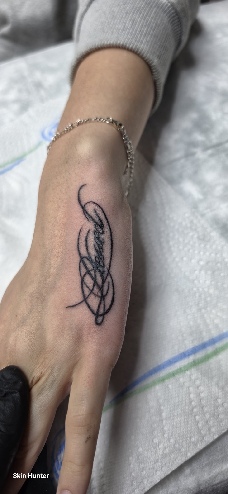 Geschwungener Schriftzug als Lettering-Tattoo auf der Hand