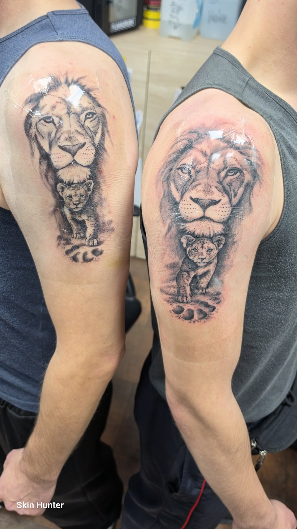 Zwei Löwen mit Jungtier als Partner-Tattoo an zwei Oberarmen