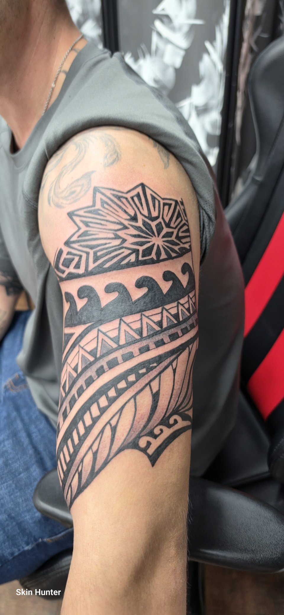 Maori-Tattoo mit Wellen und Sonnenmuster am Oberarm