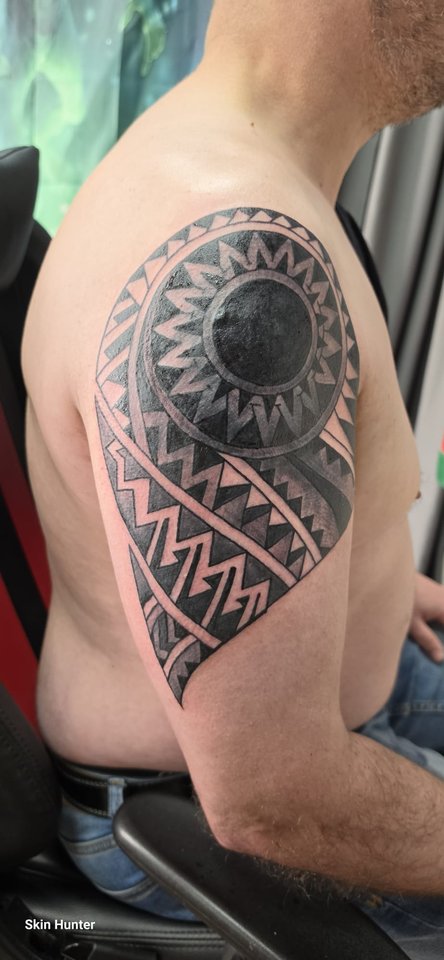 Polynesisches Tattoo mit Sonne und Mustern auf der Schulter