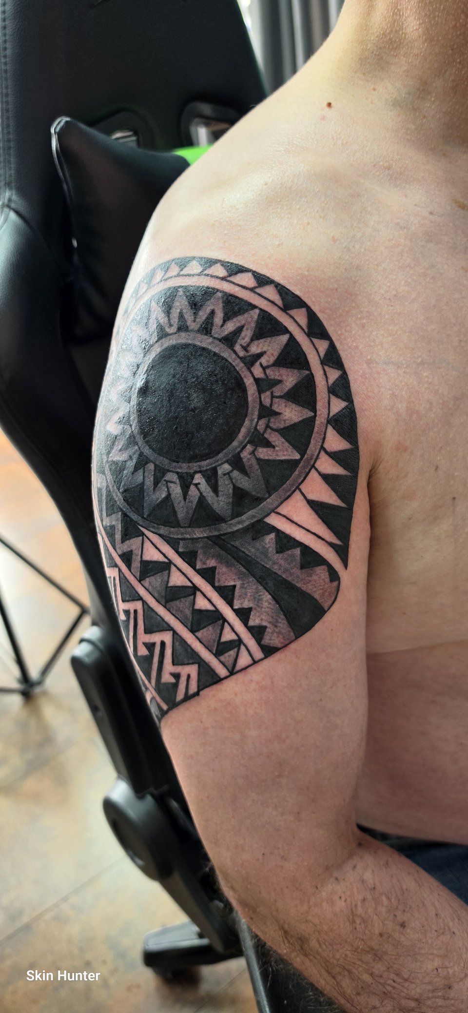 Maori-Tattoo mit Sonne und Mustern über Schulter und Oberarm